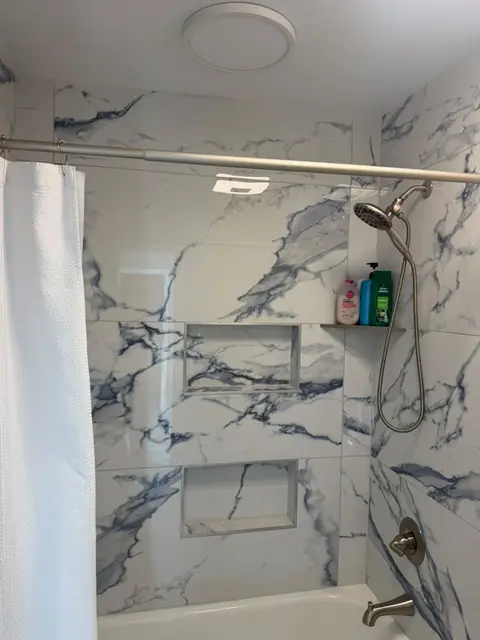 Tub-shower with blue-veined marble-look tile and double niche