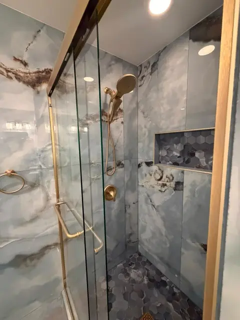 Walk-in shower with gold-frame glass door and mosaic floor