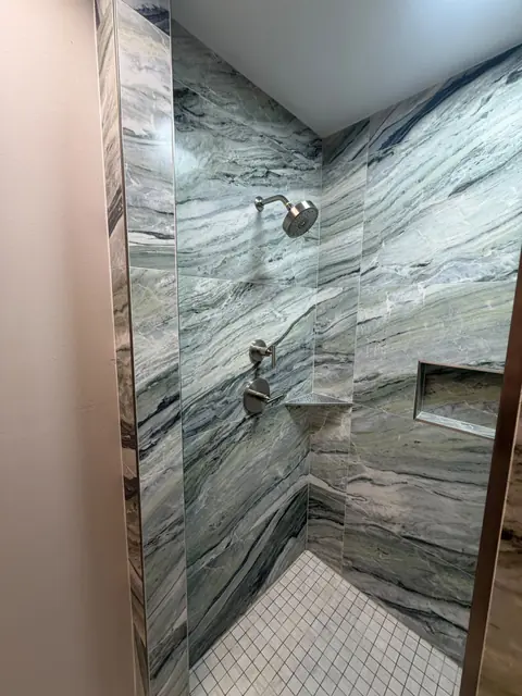 Walk-in shower with large-format marble-look tile and recessed niche