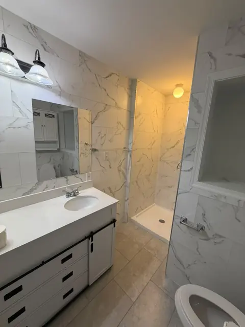 Bathroom remodel with white marble-look tile and walk-in shower